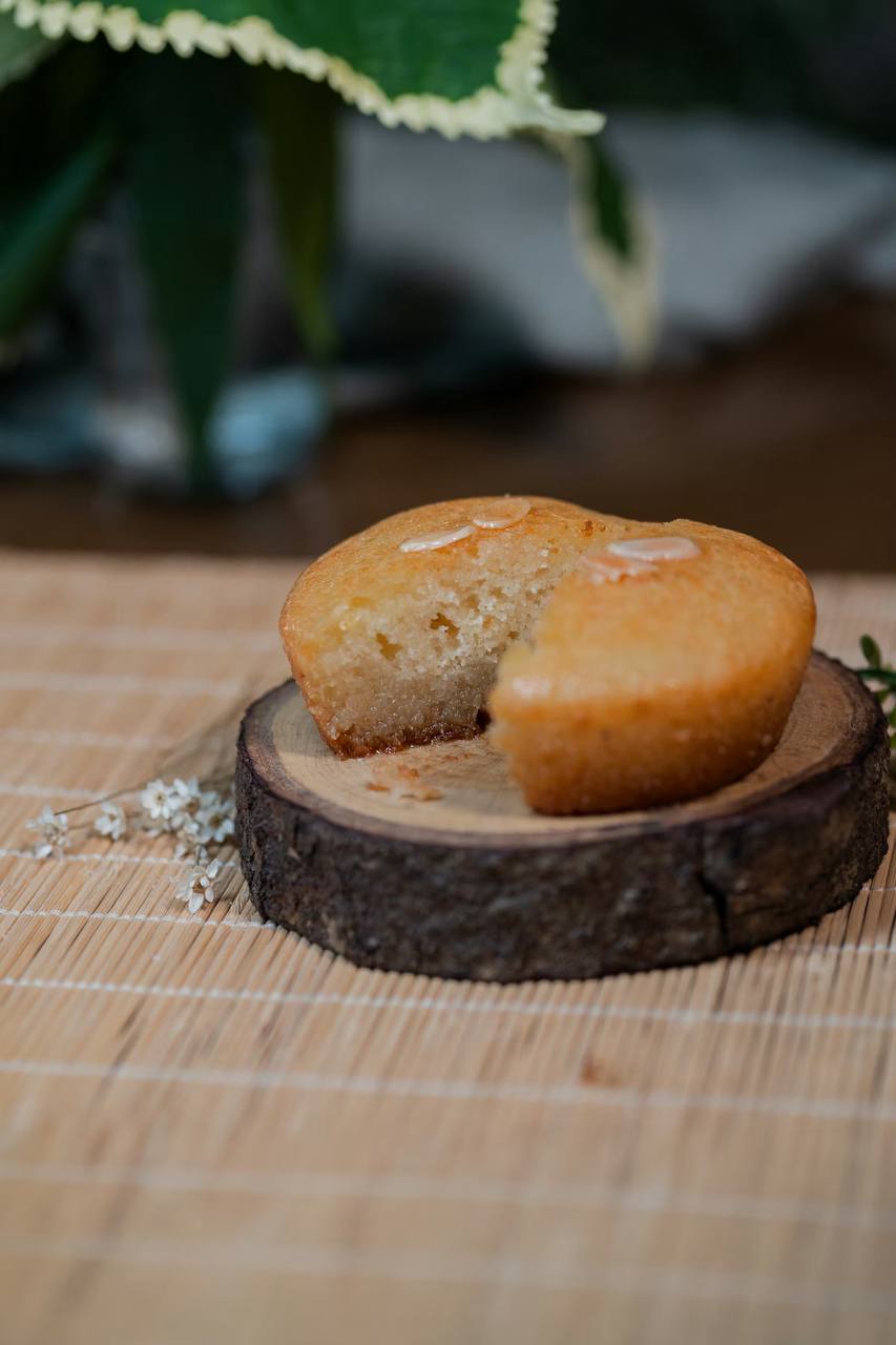 A golden bolo de arroz rice-flour muffin on a wooden slice.