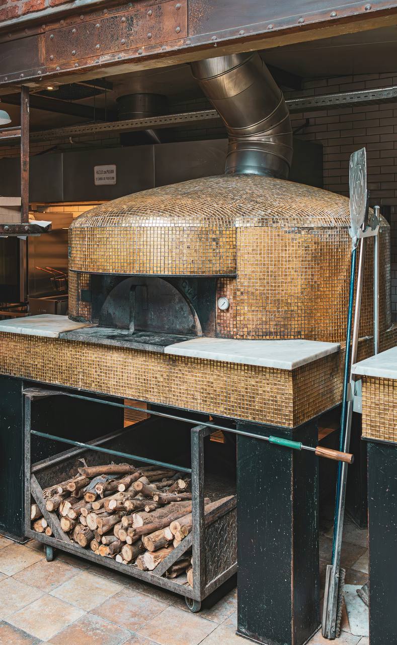 A traditional domed wood-fired oven at Bolo Bakery with firewood stacked underneath.