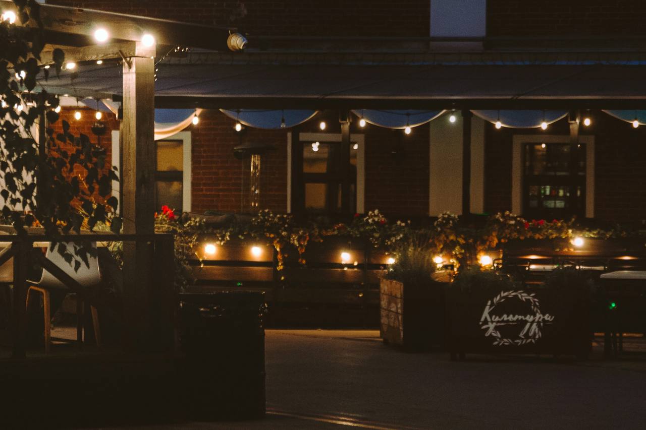 The exterior of Embers and Oak at dusk, string lights strung across a brick patio.